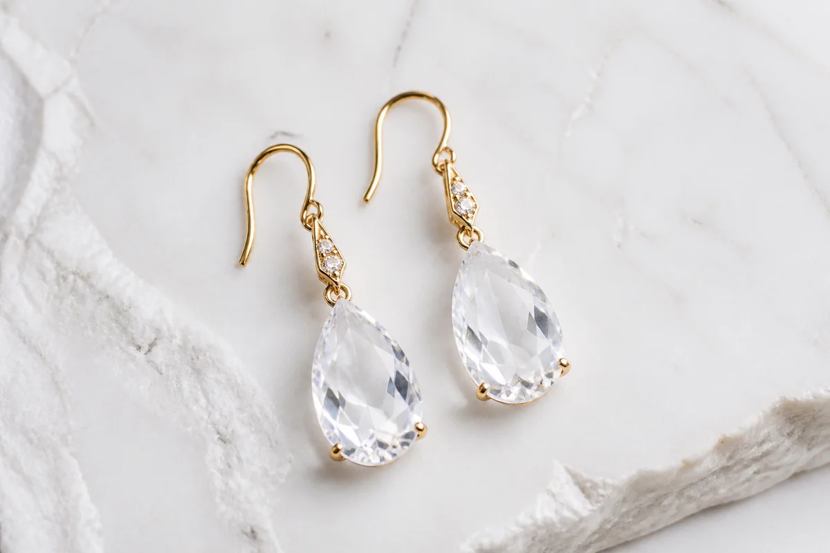 Pair of crystal drop earrings on white marble surface